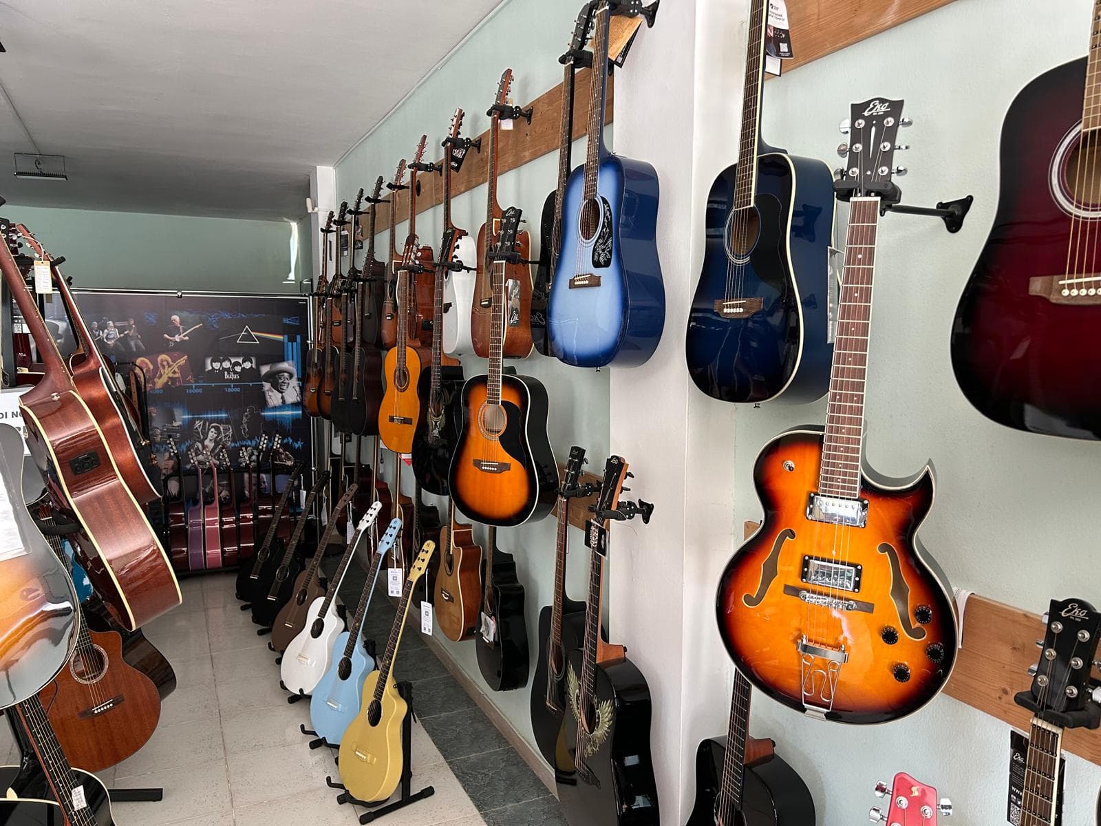 La parete con chitarre acustiche, classiche e semiacustiche nel negozio Fidelta Music